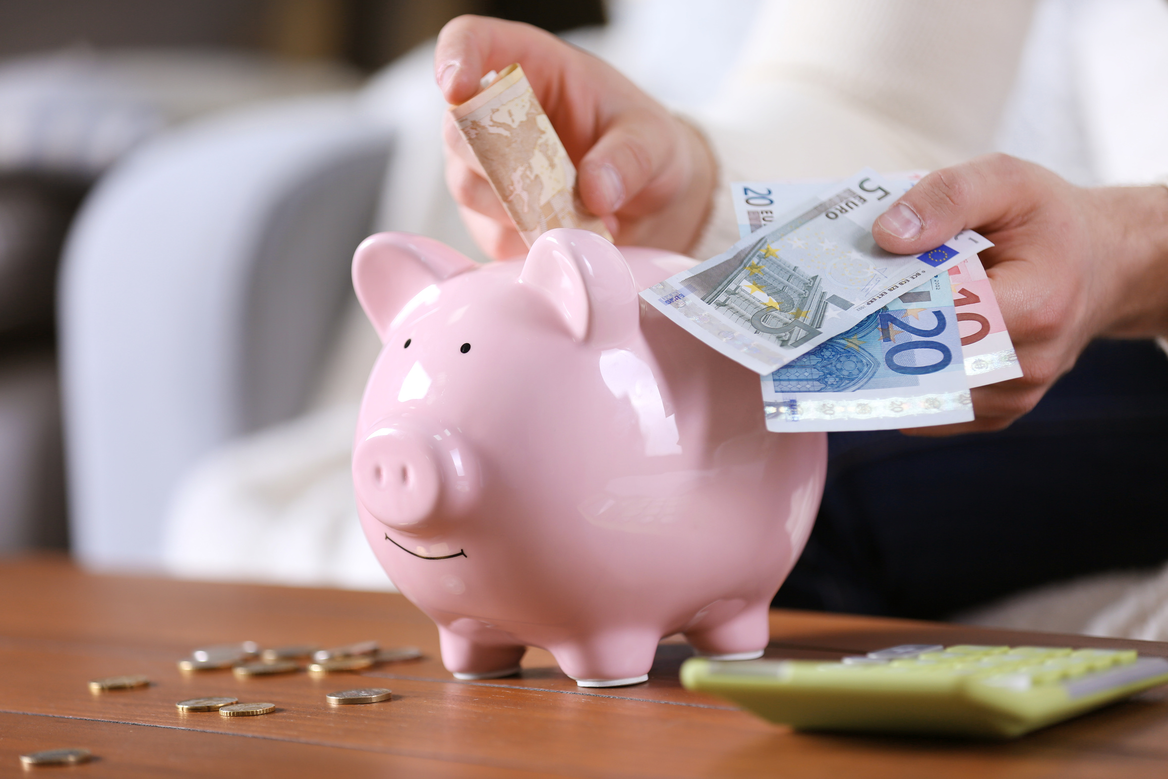 Ein Sparschwein wird mit Geldscheinen und Münzen gefüllt.